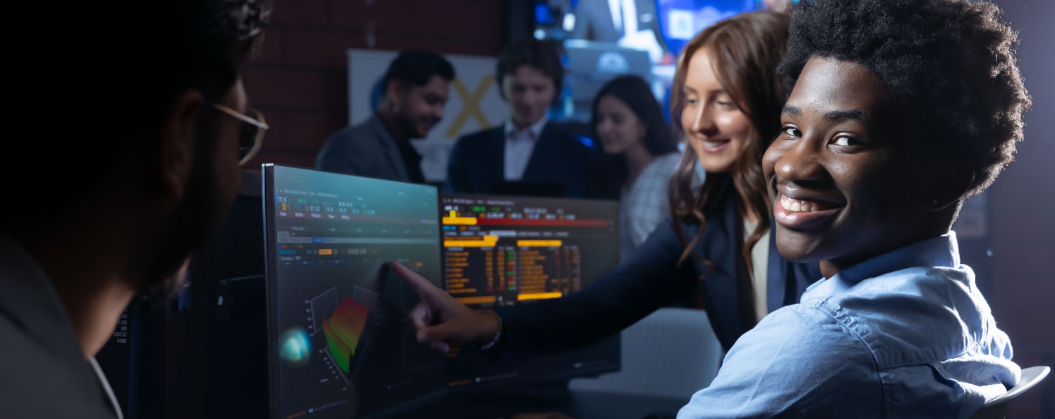 Student in front of computer screen looking at camera
