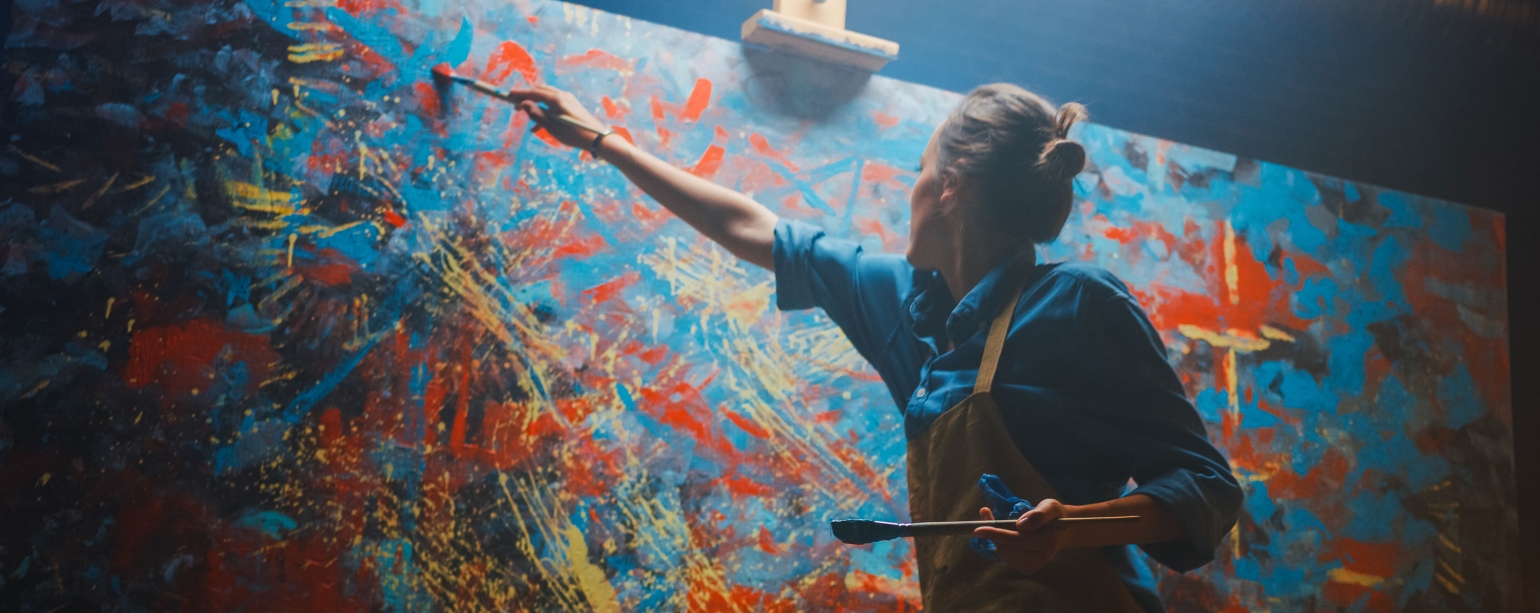 An artist reaching high and painting on canvas