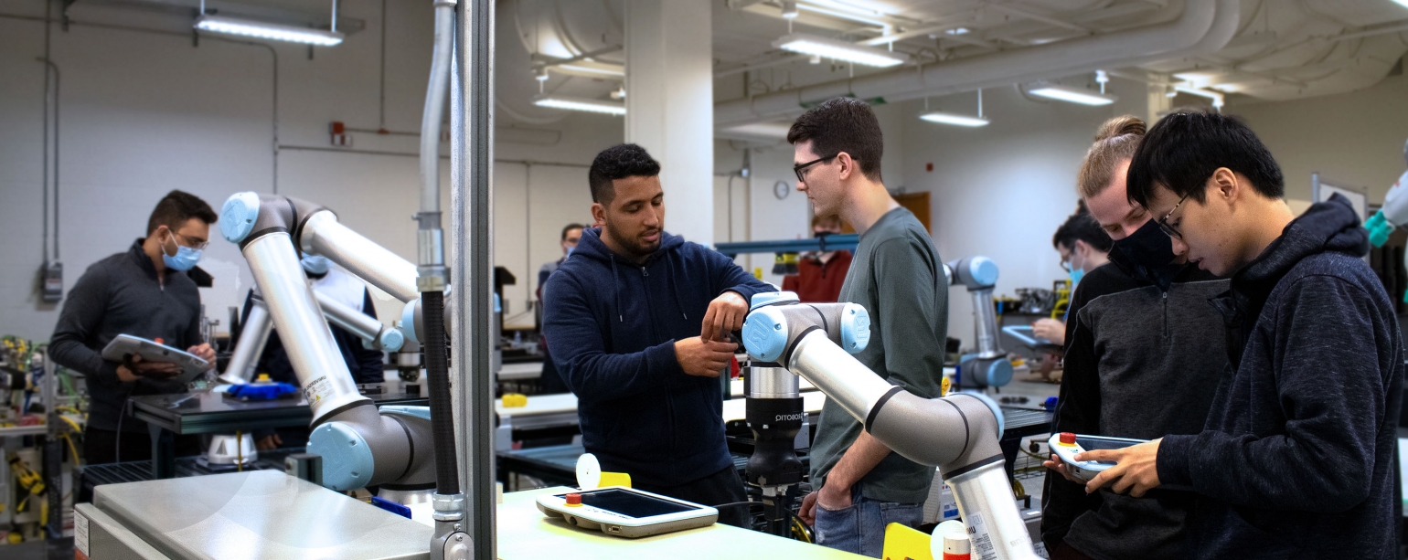 Two students working on automated machine in engineering lab