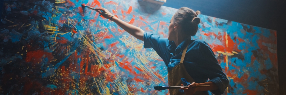 An artist reaching high and painting on canvas