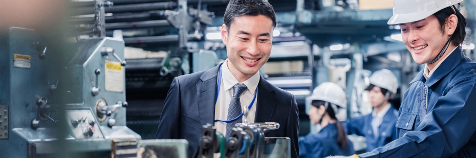Two people in a manufacturing setting smiling