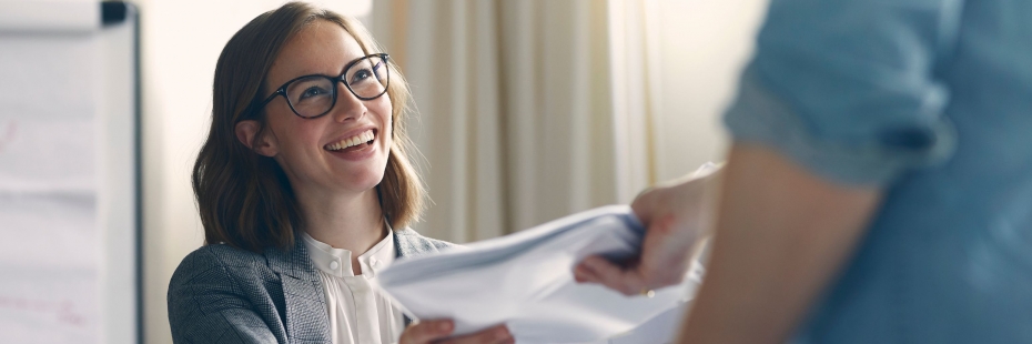 Young woman passing a report to another individual